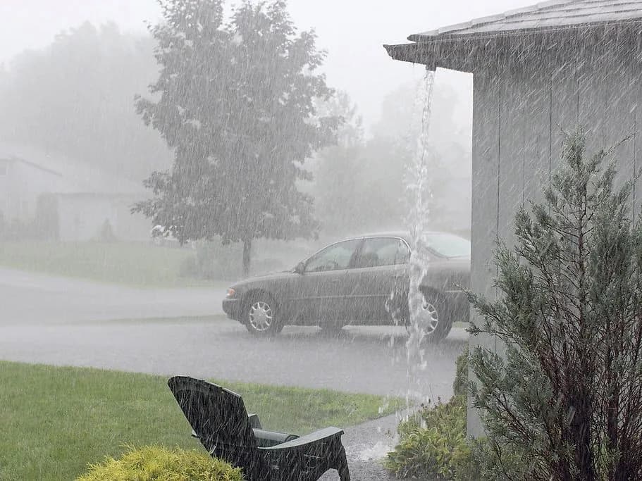 Rain pouring off a roof line where gutters cannot carry the water